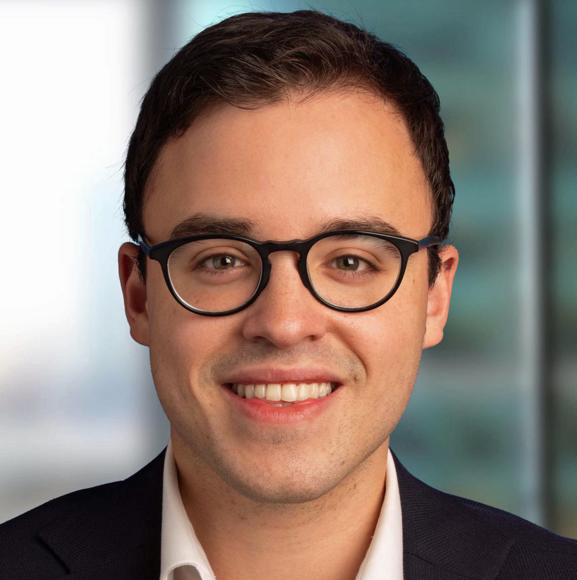 Smiling young adult male wearing glasses in a professional headshot.