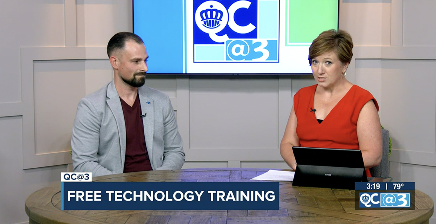 Two presenters seated at a news desk with a TV graphic reading "FREE TECHNOLOGY TRAINING."
