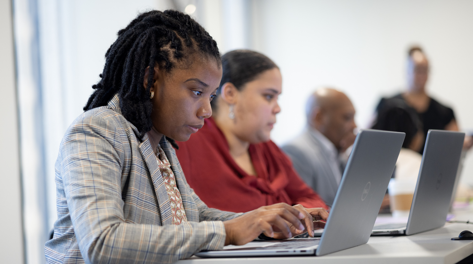 Adult learners focused on laptops in a classroom-style training session.