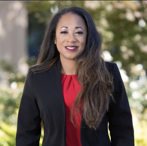 Smiling woman in business attire standing outside.