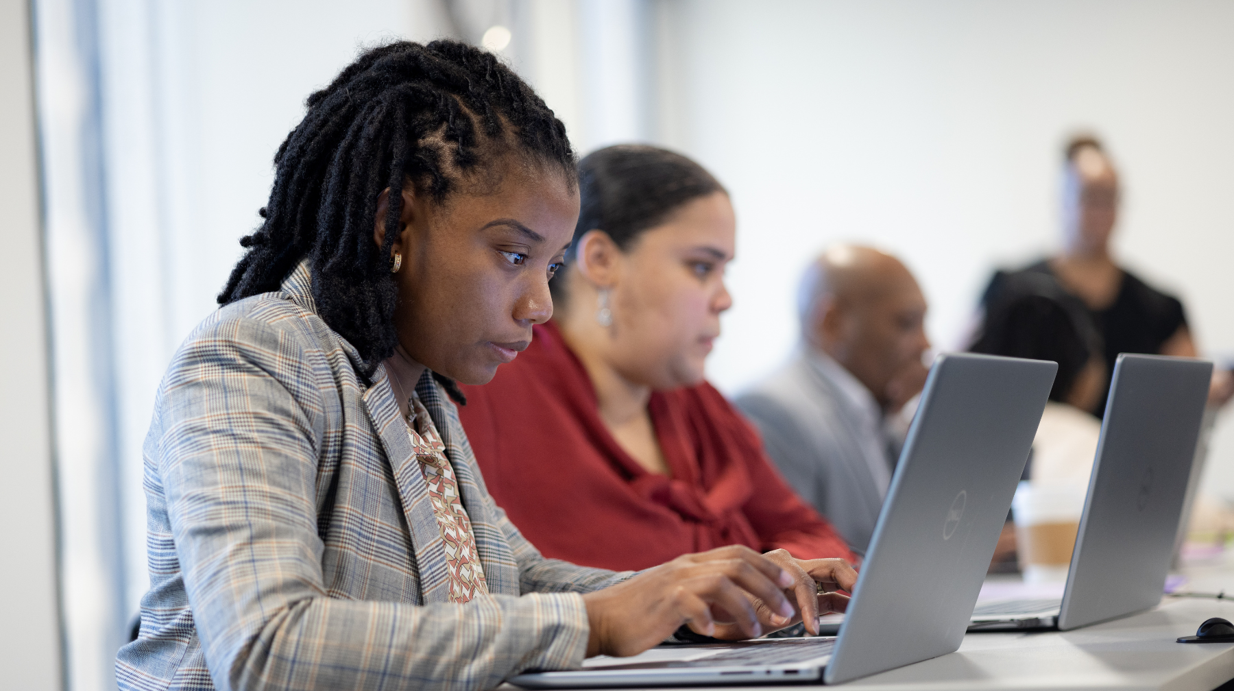 Adult learners focused on laptops in a classroom-style training session.
