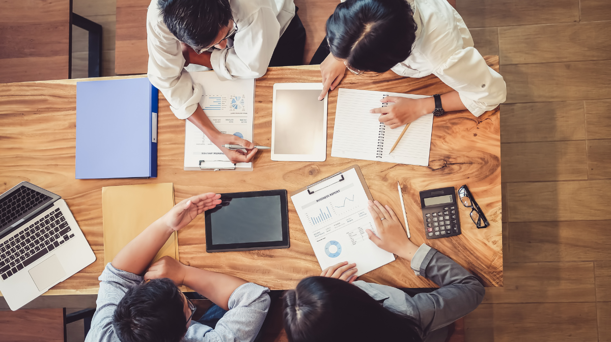 Four young professionals collaborating around a table reviewing analytical reports.