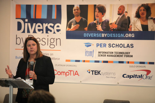 Woman speaking at a podium standing in front of a Per Scholas and "Diverse by Design" banner with sponsor logos.