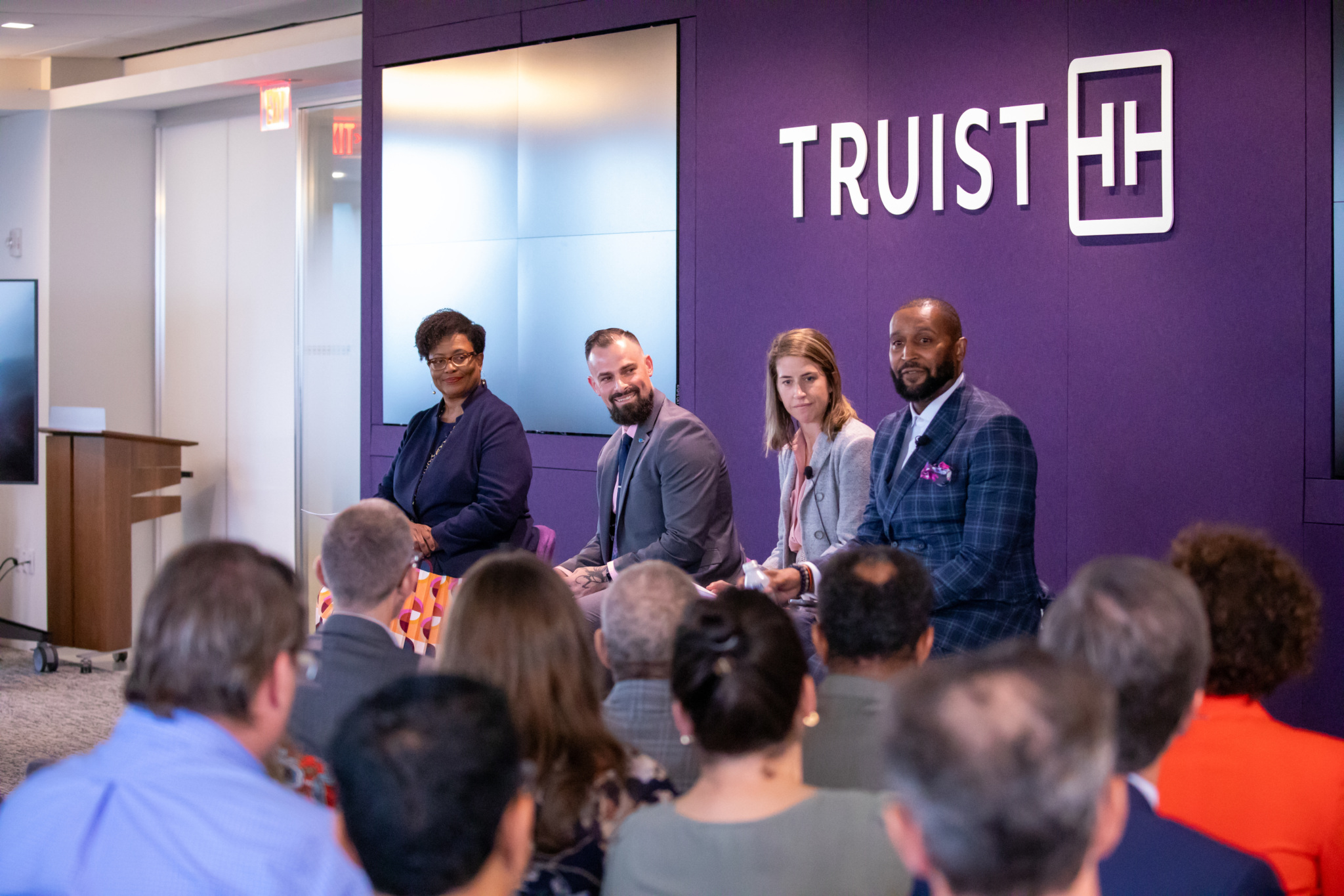 Truist logo on a purple wall with four panelists seated and speaking to an audience.