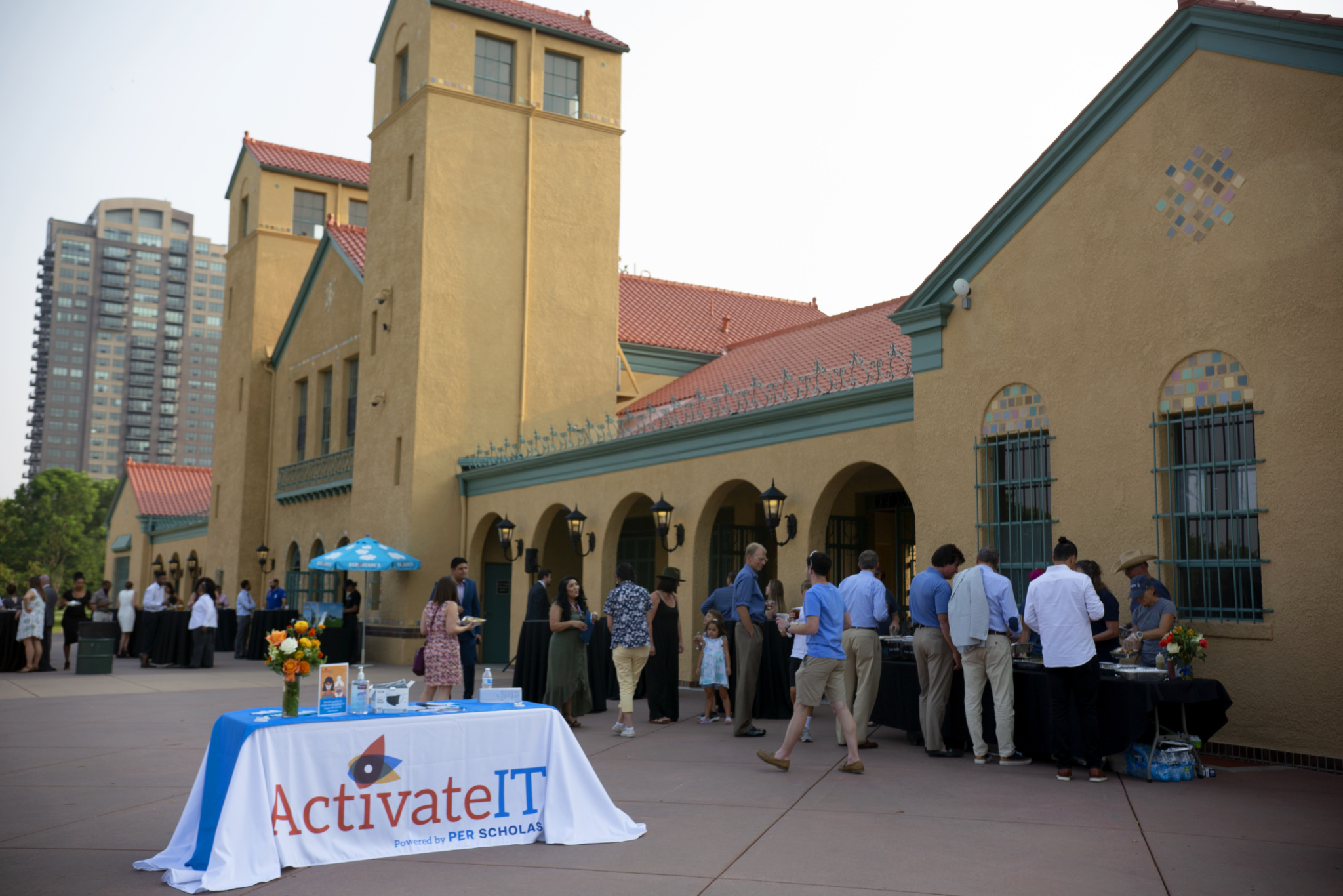 Outdoor reception with people getting food beside a building, with an ActivateIT table in the foreground.