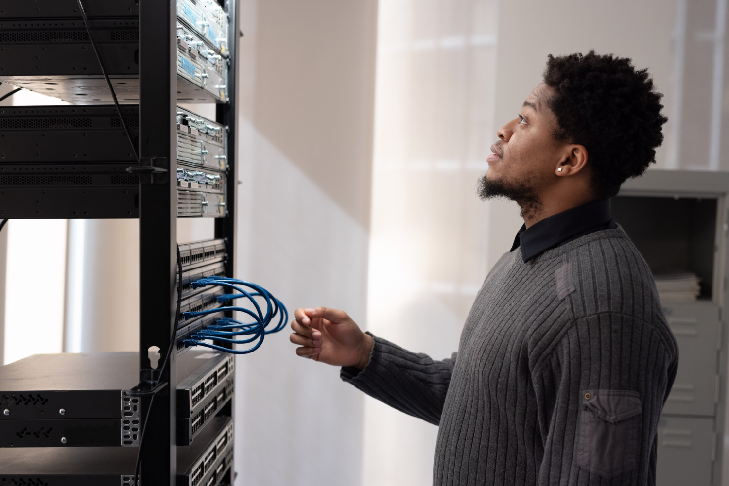 A technician standing at a server rack, checking network cables and equipment.