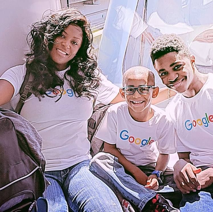 Three smiling people wearing Google t-shirts sit closely together while posing for a picture.