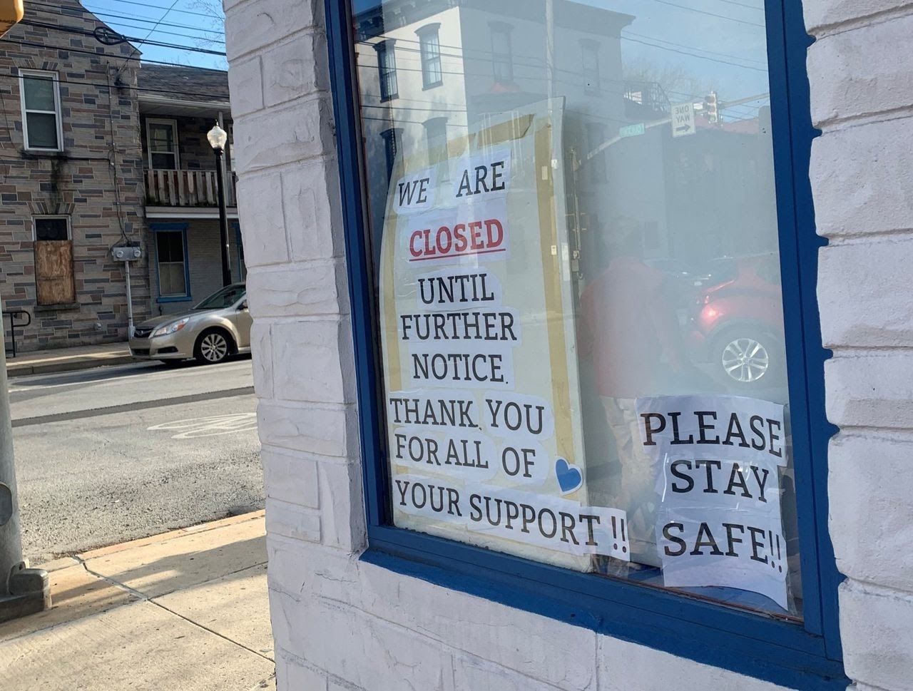 Window sign reading "WE ARE CLOSED UNTIL FURTHER NOTICE. THANK YOU FOR ALL OF YOUR SUPPORT!!" with a separate smaller sign saying "PLEASE STAY SAFE!".