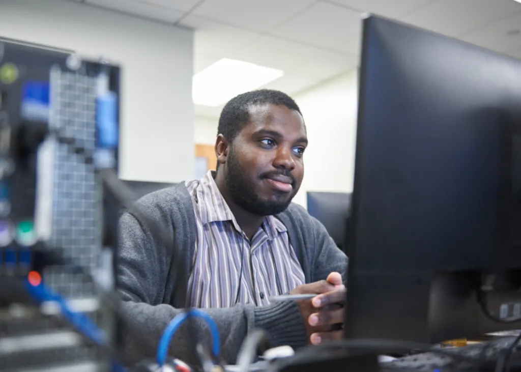 Adult student focused at a computer monitor in a classroom.