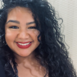 Smiling young woman with curly hair, facing the camera in a headshot.