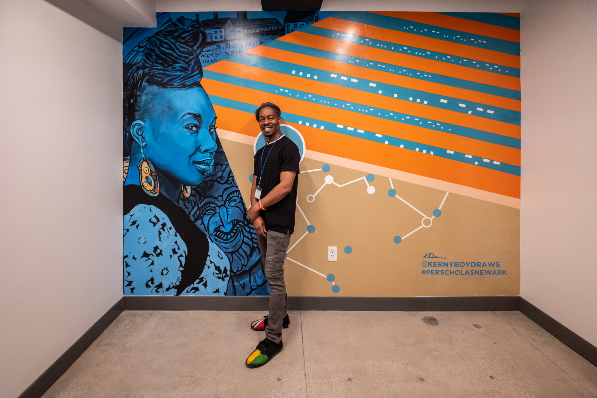 Student standing and smiling in front of a colorful mural.
