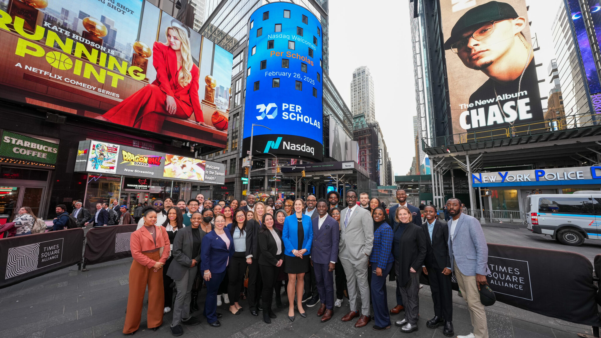 A diverse group of Per Scholas staff and supporters standing together in Times Square beneath a large Nasdaq screen displaying "Per Scholas" and the date February 26, 2025.