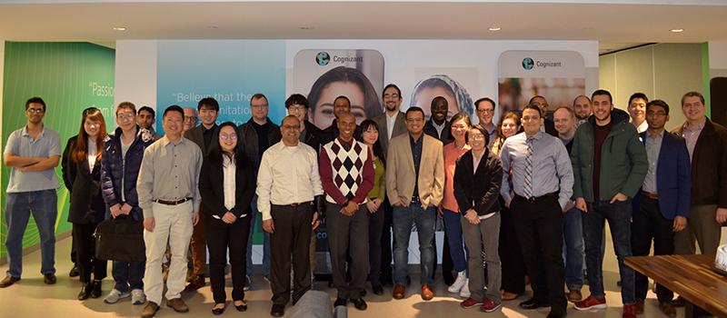A diverse group of about 25 adults standing together in an office lobby, smiling for a group photo.