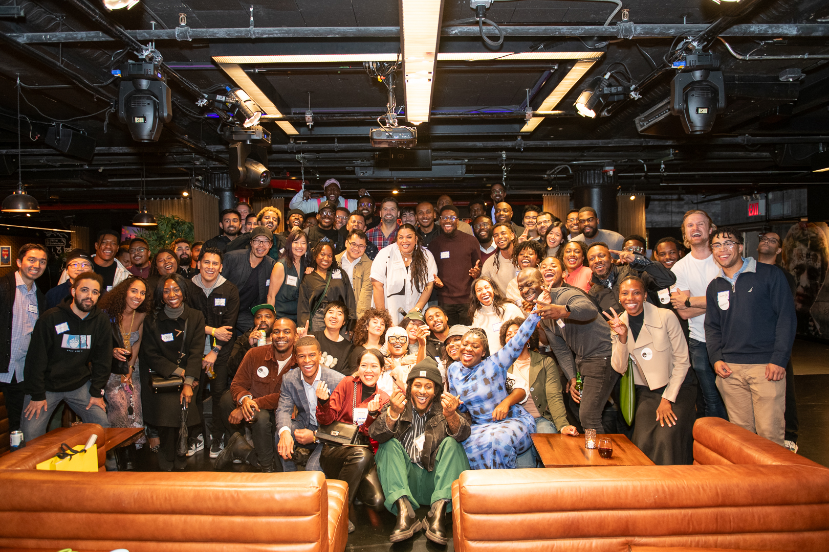 Large diverse group of smiling adults posing together at an indoor community event.