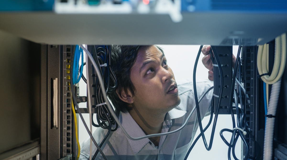 Technician inspecting cables and equipment inside a server.