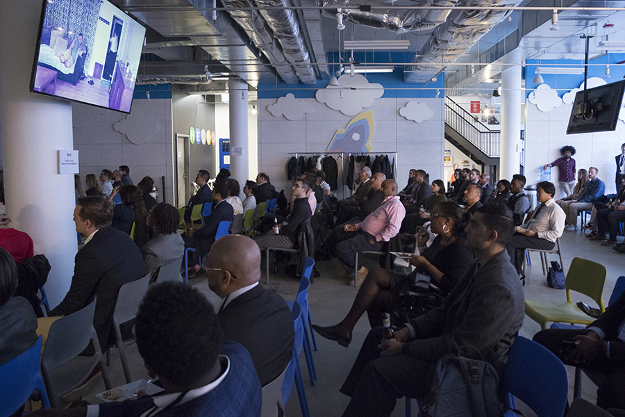 Adults seated in a room watching a presentation projected on a screen.