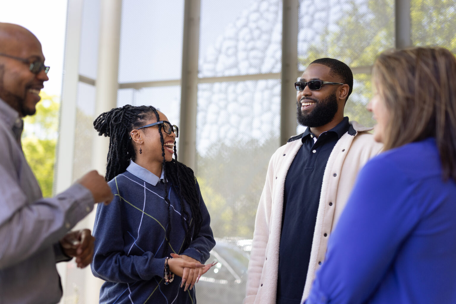 Four young professionals standing and smiling while conversing.