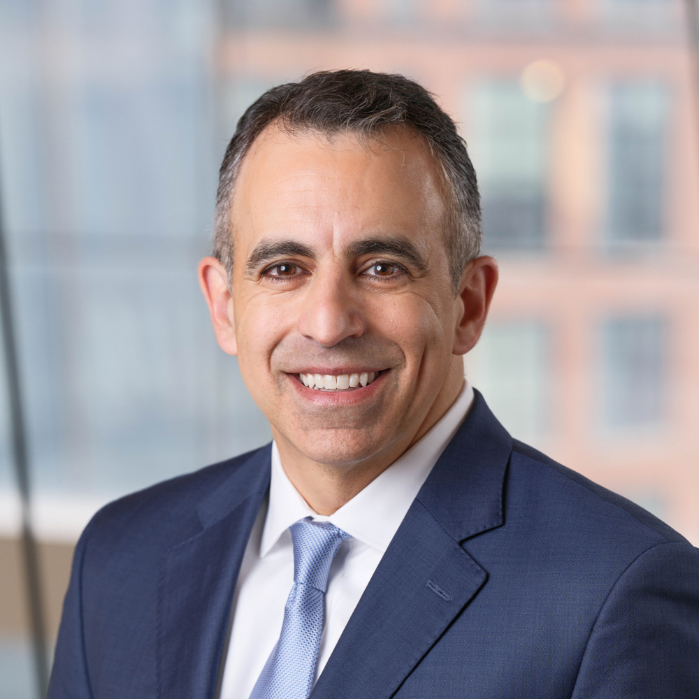 Man in business suit smiling at camera in an office setting.