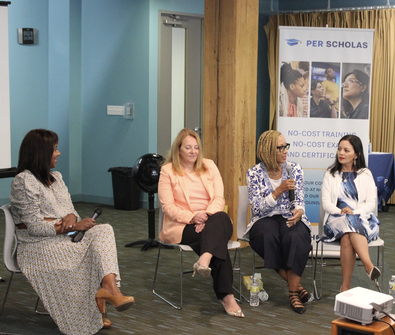 Four women seated in a panel discussion in front of a Per Scholas banner.