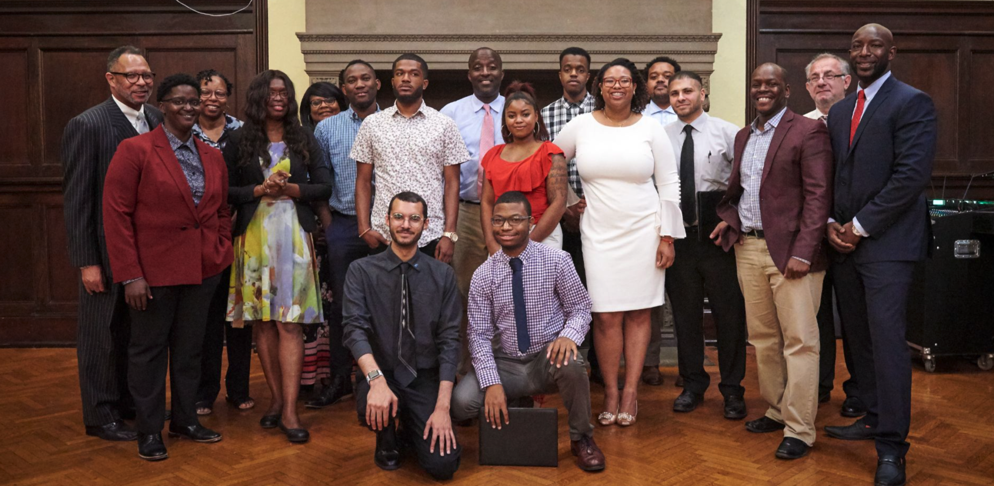 A diverse group of adults posing together in a formal room.
