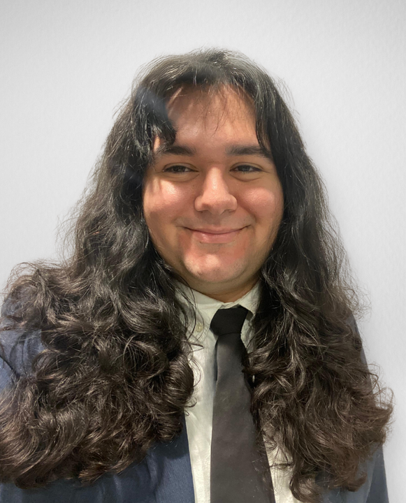 Smiling person wearing a suit and tie, facing the camera.