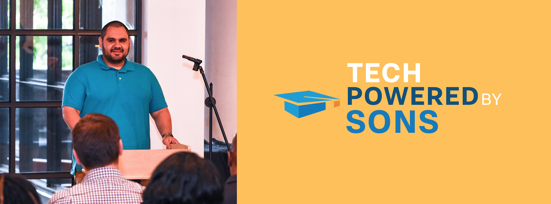 Man speaking at a podium to an audience next to the "Tech Powered By Sons" logo on a yellow banner.