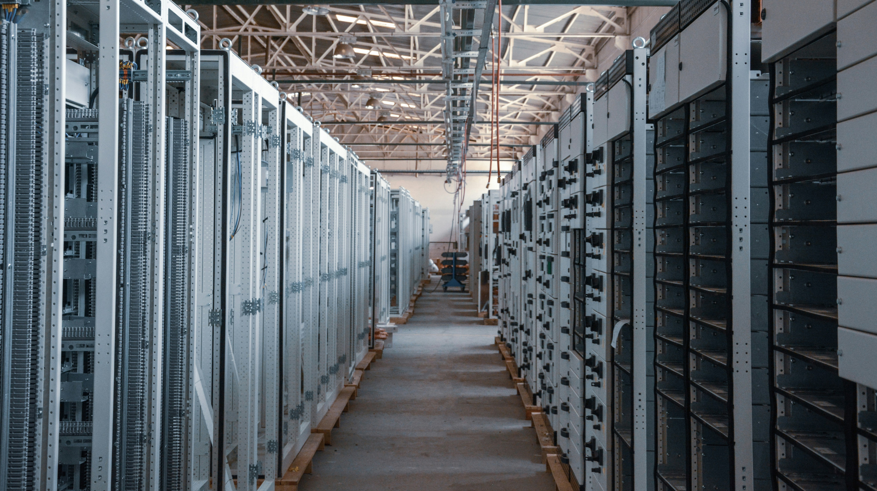 Rows of server cabinets lining a long maintenance aisle in a warehouse-style facility.