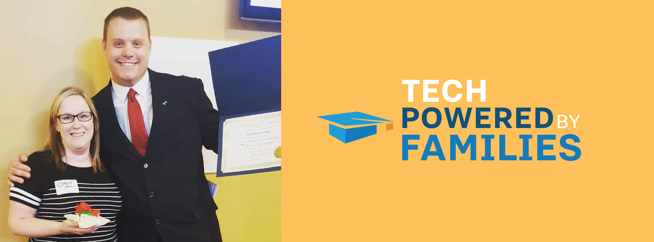 Two smiling adults posing together at an event, one holding a dessert and the other holding a certificate, next to the "Tech Powered By Families" logo on a yellow banner.
