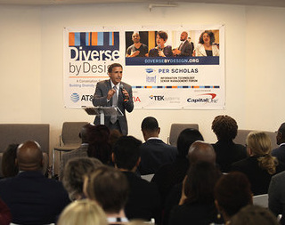 A male speaker stands at a podium addressing an audience in front of a "Diverse by Design" banner with sponsor logos.