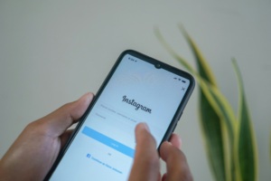Hands holding a smartphone and tapping the Instagram login screen.