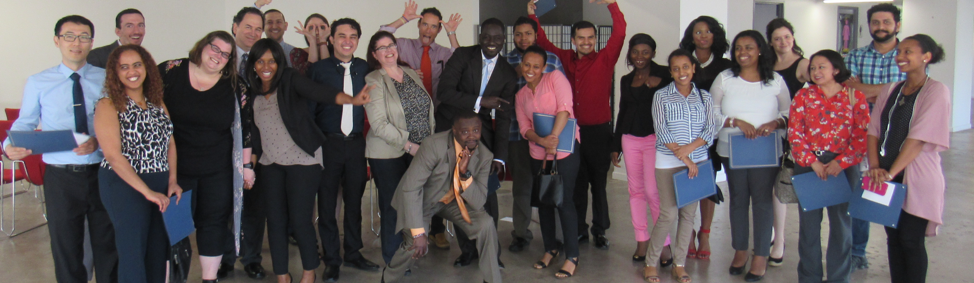 Group of adult graduates posing together, smiling and holding certificates.