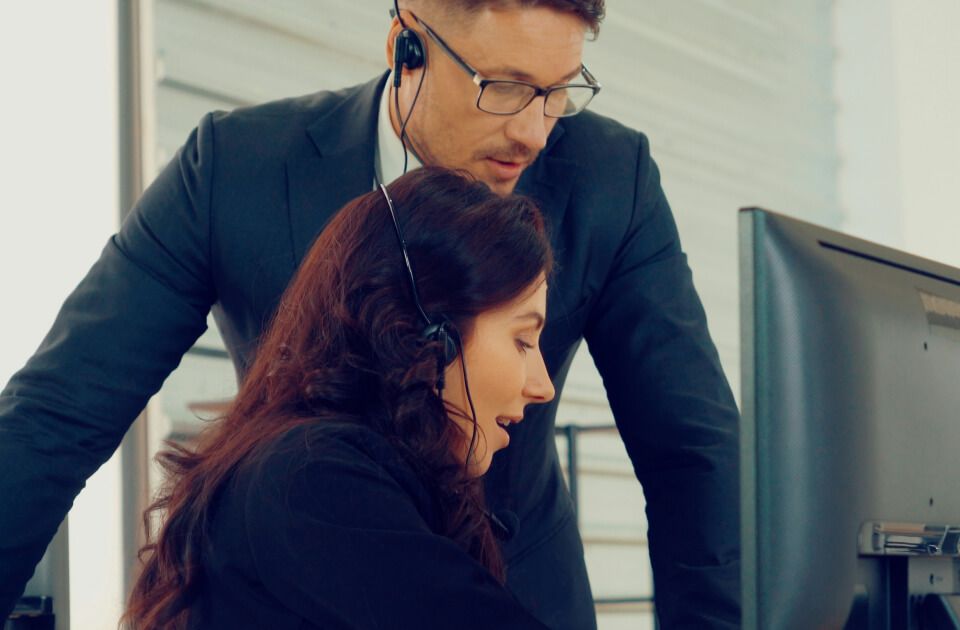 Male and female professionals working at a computer.