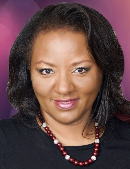 Head-and-shoulders portrait of Sharon Harris smiling, wearing a beaded necklace.