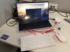 Laptop and single-board computer setup on a desk with an external keyboard, mouse, and connected cables.