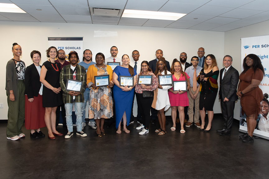 Graduates and staff stand together holding certificates at a Per Scholas graduation ceremony.
