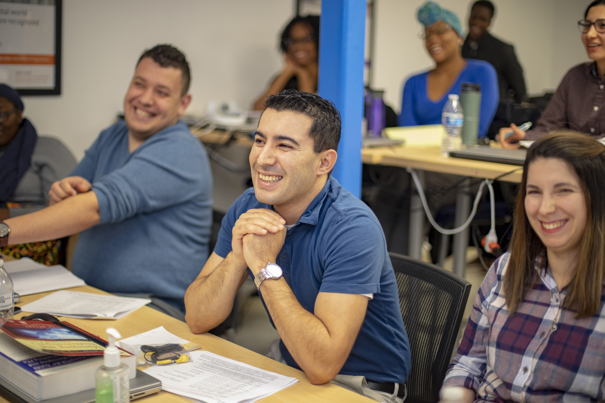Adult learners smiling and listening attentively during a Per Scholas classroom session.