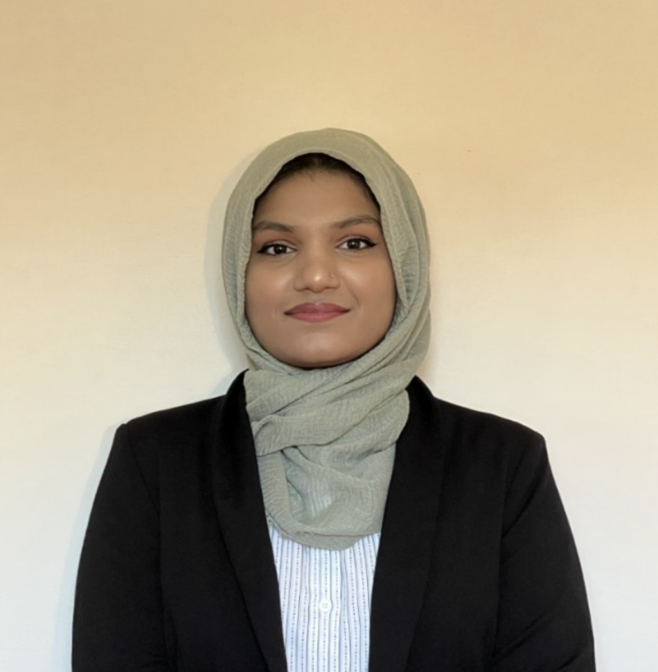 Young woman wearing a hijab and blazer, facing camera smiling.