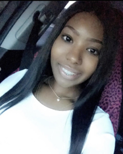 Young woman smiling at the camera from inside a car.