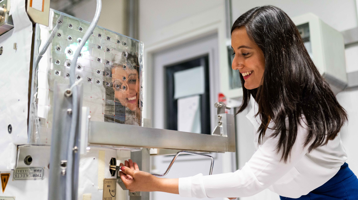 Woman smiling as she adjusts controls on a lab instrument.