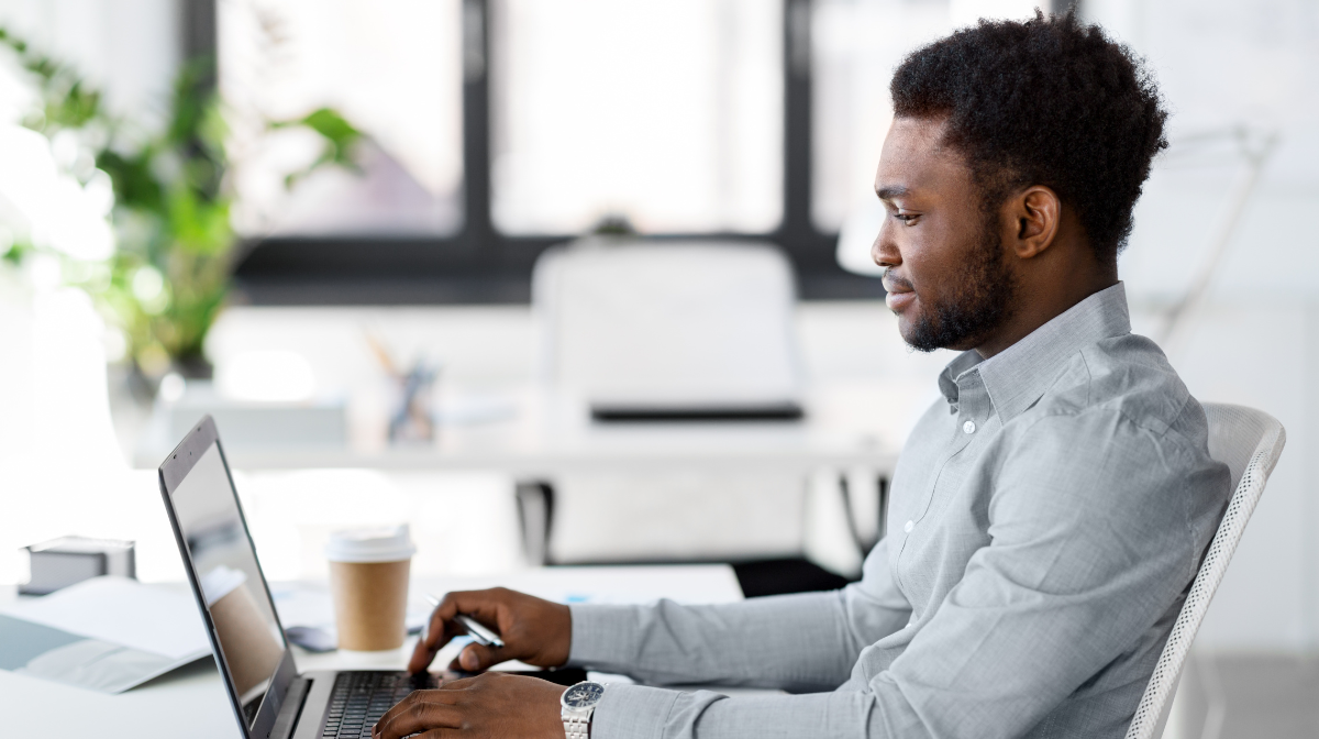 Young professional working at a laptop in a bright office, focused on his screen.