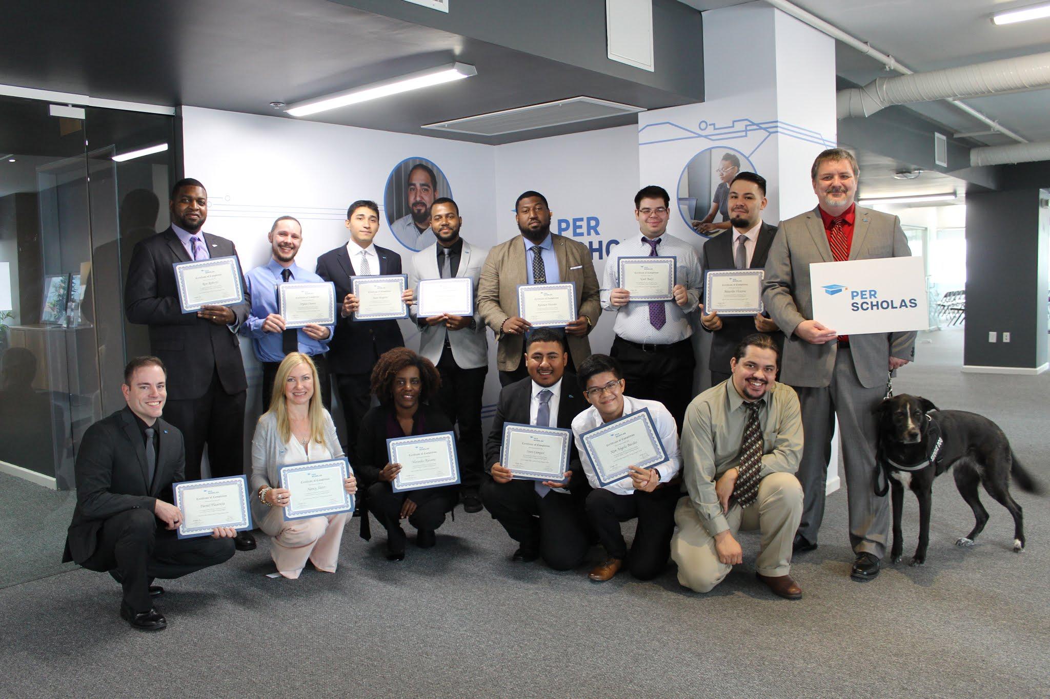 Group of adults in a training space holding completion certificates, smiling for a graduation photo.