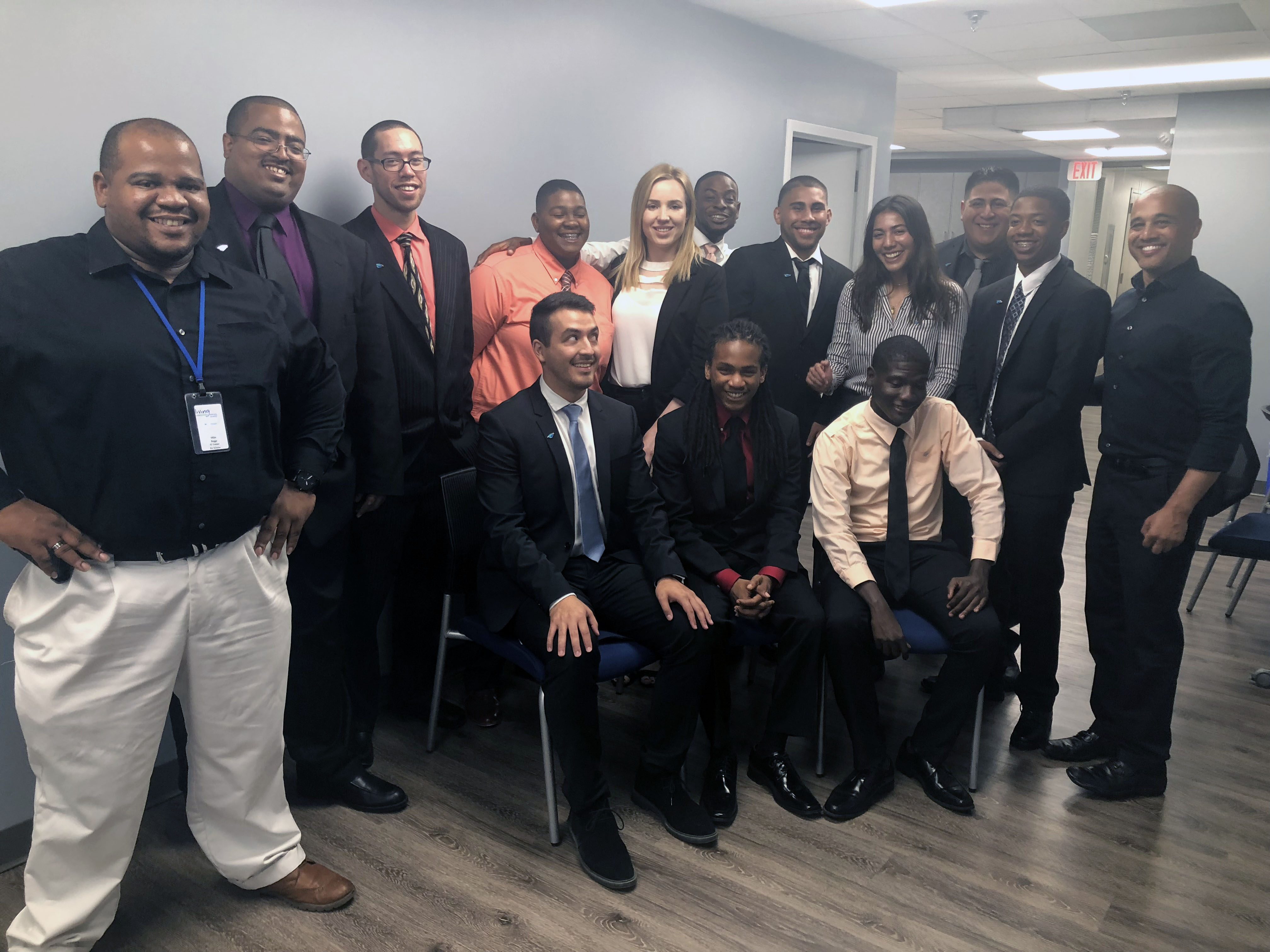 Group of Per Scholas graduates smiling for a picture together in a classroom.