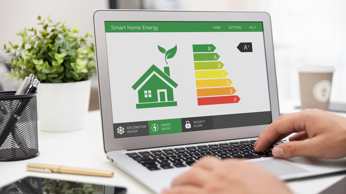 Person typing on a laptop displaying a Smart Home Energy dashboard with a green house icon.