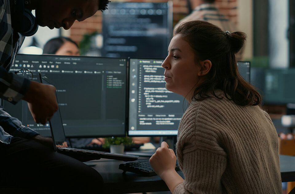 Team collaborating in front of computer screens displaying code.