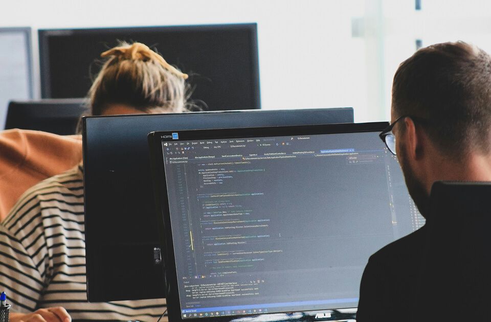 Students coding on computer screens in classroom.