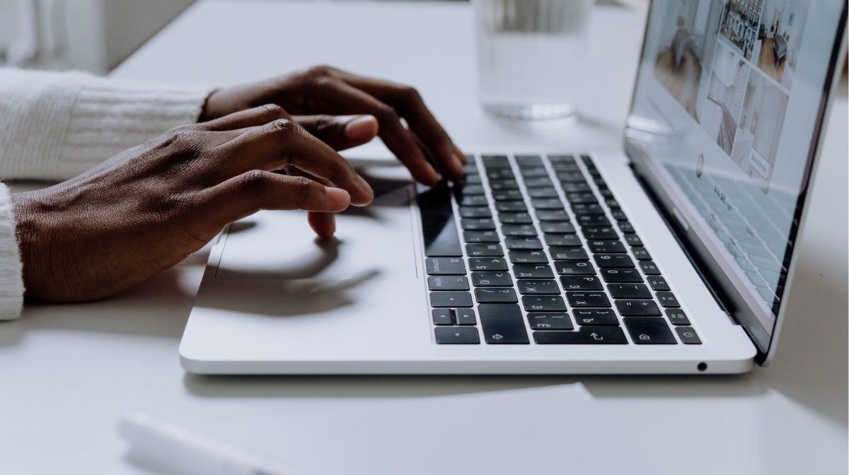 Hands typing on a laptop keyboard at a desk.