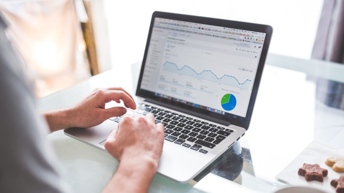Person using a laptop showing analytics with a line chart and pie chart.