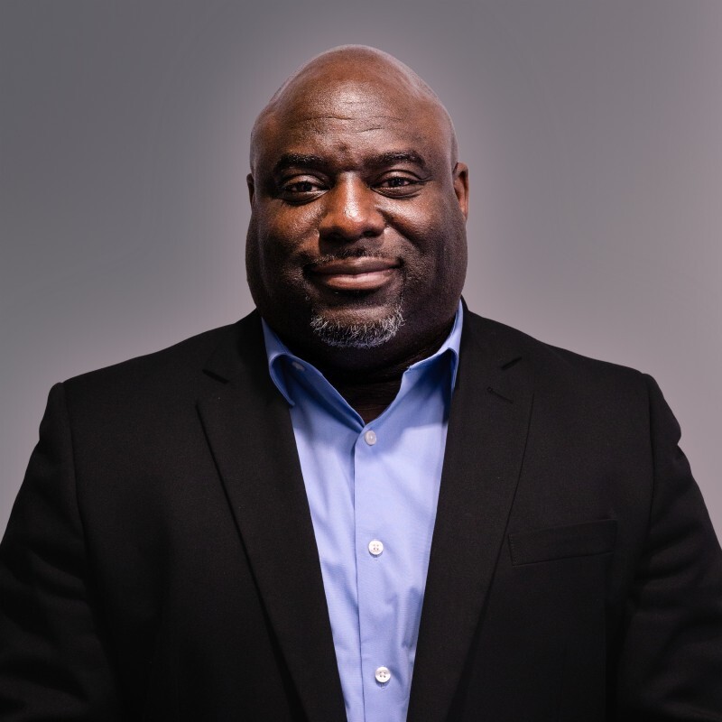 Headshot of Craig Curry, smiling in a suit jacket and collared shirt.