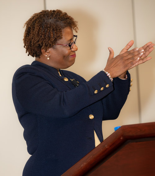 Woman at a podium clapping.