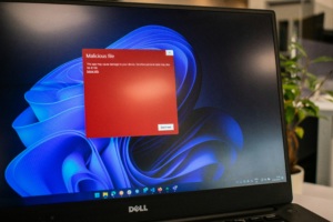 Laptop screen showing a Windows desktop with a red security alert dialog labeled Malicious file.